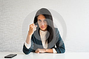 Young cute caucasian brunette business woman director in office show fist to camera at work for employee resentful angry serious