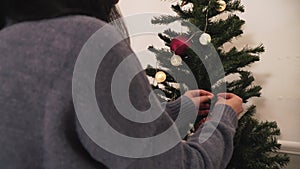 Young cute couple decorating the Christmas tree in the room before holiday. New Year and Christmas time concept. Happy