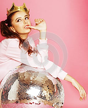 Young cute disco girl on pink background with disco ball and crown