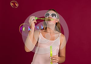 Young cute girl blows soap bubbles, isolated