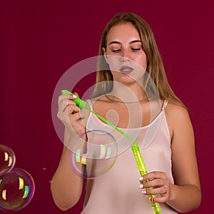 Young cute girl blows soap bubbles, isolated