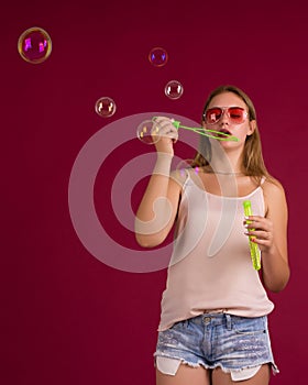 Young cute girl blows soap bubbles, isolated