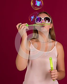 Young cute girl blows soap bubbles, isolated