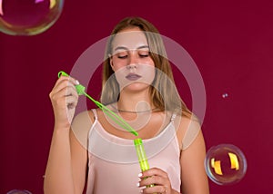 Young cute girl blows soap bubbles, isolated