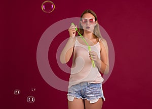 Young cute girl blows soap bubbles, isolated