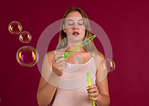 Young cute girl blows soap bubbles, isolated