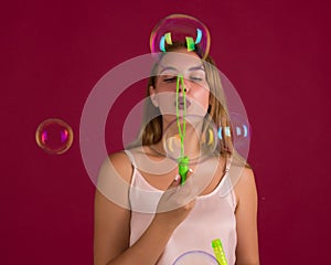 Young cute girl blows soap bubbles, isolated