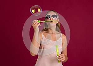 Young cute girl blows soap bubbles, isolated