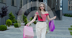 A Young Cute Girl In Casual Clothes, Sunglasses And Hair Hoop Standing In A Front Of Shopping Mall With Bags In Hands.