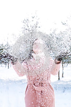Young cute girl with durk hair has fun in snowy weather in winter in the park. photo