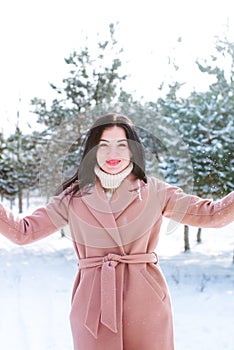 Young cute girl with durk hair has fun in snowy weather in winter in the park. photo