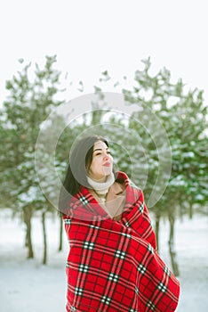 Young cute girl with durk hair in red scarf has fun in snowy weather in winter in the park. photo