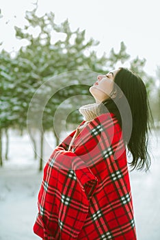 Young cute girl with durk hair in red scarf has fun in snowy weather in winter in the park. photo