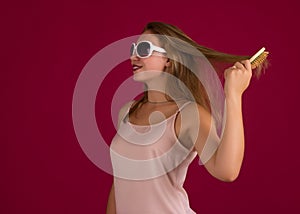 Young cute girl with hair brush, studio