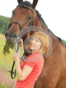 Young cute girl with her horse in field