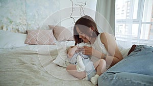 Young cute girl playing with her son on the bed. A young mother is playing with a baby on the bed.