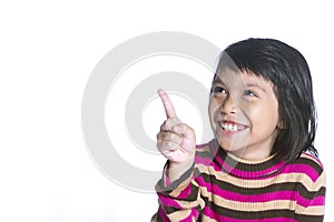 A young cute girl is pointing in the corner. She also looks there and smiles. over white.