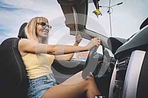 Young cute girl preens while driving. blonde admires herself in mirror. Happy female driver behind the wheel. woman lowers the sun