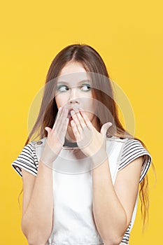 Young cute girl scaredly covers her mouth with palms