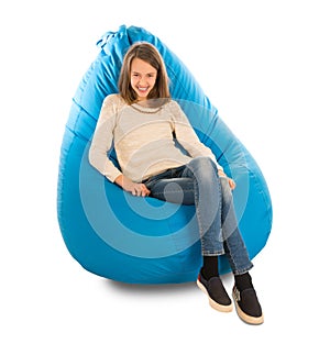 Young cute girl smiling while sitting on blue beanbag