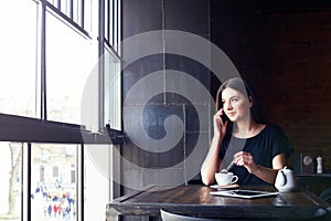Young cute girl talking on the phone in cafe.