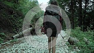 Young cute girl turns around and smile while hike by white cobblestones track in the summer forest, taken from the shoes