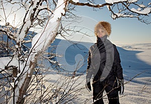 Young cute happy laughing female woman model playing with snowy trees branches smiling from fun and joy in falling down white snow