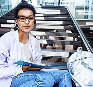 Young cute indian girl at university building sitting on stairs