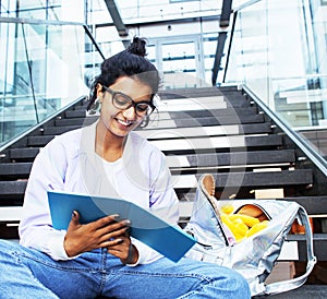 Young cute indian girl at university building sitting on stairs