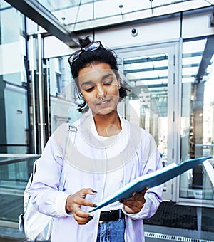 Young cute indian girl at university building sitting on stairs