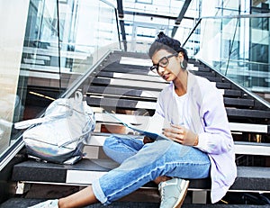 Young cute indian girl at university building sitting on stairs