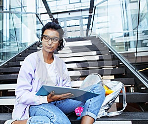 Young cute indian girl at university building sitting on stairs