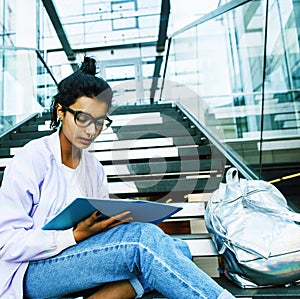 Young cute indian girl at university building sitting on stairs