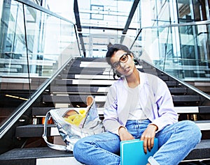 Young cute indian girl at university building sitting on stairs