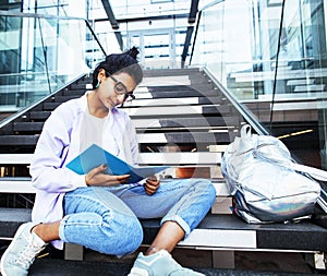 Young cute indian girl at university building sitting on stairs