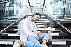 Young cute indian girl at university building sitting on stairs