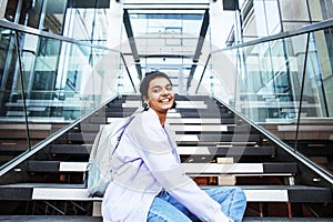 Young cute indian girl at university building sitting on stairs