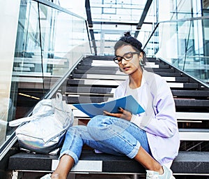 Young cute indian girl at university building sitting on stairs