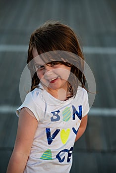 Young cute little girl on the boardwalk looking at camera smiling