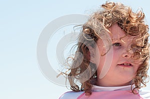 Young cute little girl playing at the seaside running into the surf on a sandy beach in summer sunshine