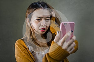 Young cute and sad Asian Korean girl feeling broken heart and desperate holding mobile phone suffering relationship break up