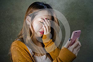 Young cute and sad Asian Korean girl feeling broken heart and desperate holding mobile phone suffering relationship break up