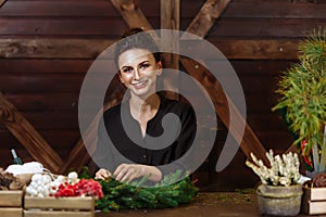 Young Cute smiling Woman designer preparing Christmas Evergreen Tree Wreath. Manufacturer of Christmas decor with their