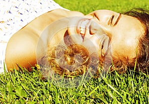 Young cute summer girl on green grass outside relaxing happy smiling close up, lifestyle people concept