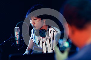 Young and cute teen boy playing guitar in rocording room studio