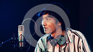 Young and cute teen boy playing guitar in rocording room studio