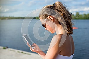 Young cute teen girl reading sms on her smartphone, view from be