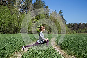 Young cute teenage girl doing stretching exercises in nature