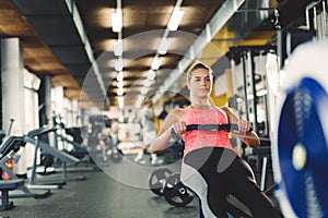 Young cute woman doing exercises with rowing machine