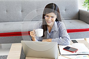 Young Cute Woman feels happy with Coffee Cup while video call Meeting on Work For Home Period.